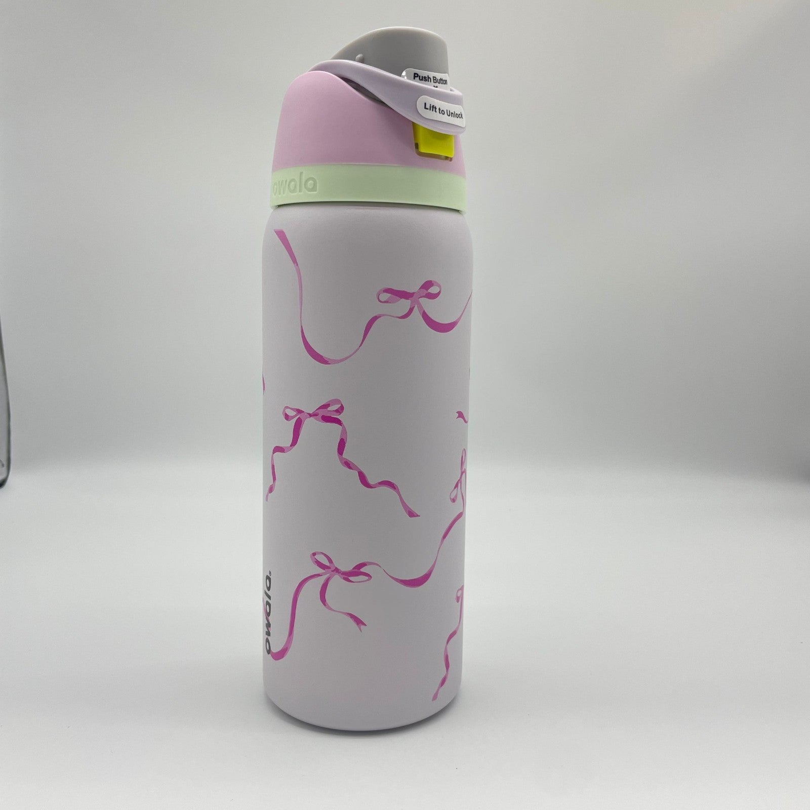 32oz Owala FreeSip water bottle in the "Tied and True" colorway, featuring a pink bow ribbon print