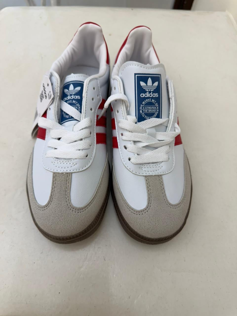 white and red Adidas Samba OG sneakers feature classic serrated stripes